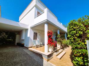 a white house with two chairs and red flowers at Apulia Beach in Leporano