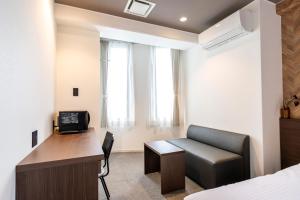 a bedroom with a bed and a desk and a couch at TapStay Hotel in Saga