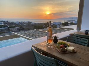 a bottle of wine and a bowl of fruit on a table on a balcony at Ostria View Resort in Mikonos
