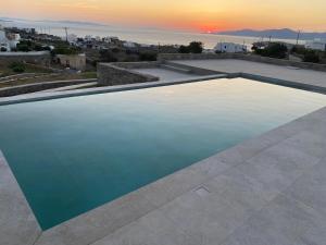 a pool of water with the sunset in the background at Ostria View Resort in Mikonos