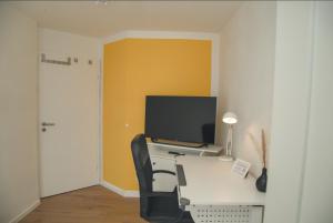 a room with a desk with a computer and a television at Rooftop Apartments Einzelzimmer in Gemeinschaftsunterkunft Weinberg R1 in Ulm