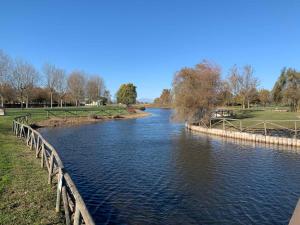 a river in a park with a wooden fence at Houses and Apt in Caorle 43917 in Caorle
