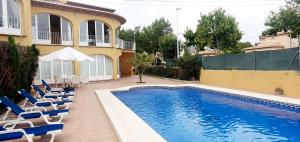 una piscina con sillas y una casa en confortable villa at only 100 meter from the beach, supermarkets and the restaurants, en Calpe