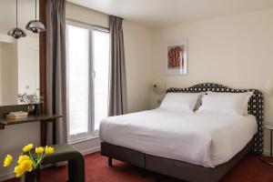 a bedroom with a bed and a large window at Hôtel Dalila- Orso Hotels in Paris