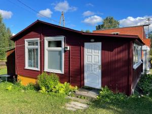 a red house with a white door and windows at Vasaras mājiņa pie Rāznas ezera Nr 2 in Kaunata +5 photos