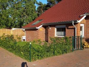 a person walking past a brick house with a fence at Ferienwohnung Noeska 85020 in Ostrhauderfehn