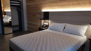 a bedroom with a large white bed and a mirror at Albergo Rusen in Borno