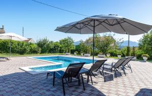 un tavolo con sedie e un ombrellone accanto alla piscina di 2 Bedroom Lovely Apartment In Citluk a Čitluk