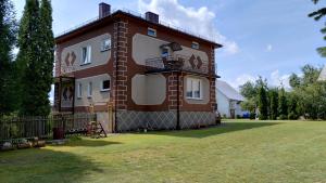 a large brick building with a balcony on a yard at Agroturystyka u Mańka in Suwałki