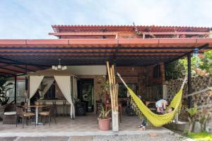 una mujer sentada en una hamaca afuera de una casa en Hosteria Florecer, en Piñas