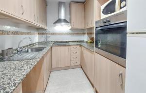 a kitchen with wooden cabinets and a sink and a dishwasher at 1 Bedroom Lovely Apartment In Vinaroz in Vinaròs