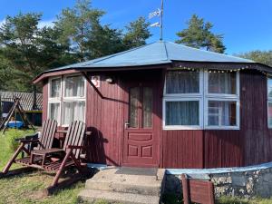 a red shed with two chairs and a table at Vasaras mājiņa pie Rāznas ezera Nr 3 in Kaunata