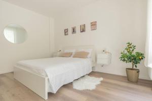 Un dormitorio blanco con una cama blanca y una planta en Libra Light, en Udine