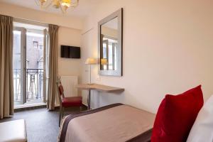 a hotel room with a bed and a desk and a mirror at H&ocirc;tel Saint Pierre in Paris