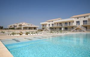 a swimming pool in front of some apartment buildings at 1 Bedroom Lovely Apartment In Marzamemi in Marzamemi