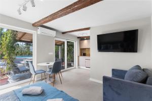 a living room with a blue couch and a tv at Süßes Ferienhaus mit Privatpool, Sonnenterrasse, BBQ in Strandnähe in Karpinjan