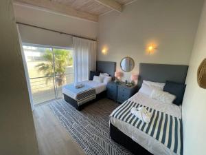 ein Schlafzimmer mit zwei Betten und einem Balkon in der Unterkunft Waterfront Cottage B2 in Swakopmund