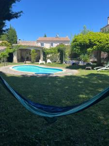 a hammock in a yard next to a swimming pool at Suite Zen Grand Lit in Pierrelatte