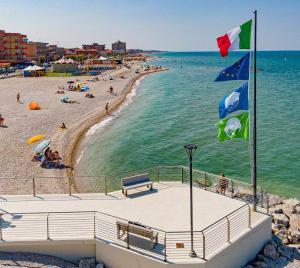 a beach with people on the water and flags at Casa di Sveva in Marotta