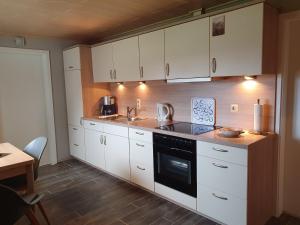 a kitchen with white cabinets and a sink and a stove at Ferienwohnung Kanalblick 35520 in Uplengen +9 photos