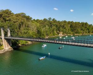 eine Brücke über einen Fluss mit Booten im Wasser in der Unterkunft Charmante maison de vacances - Le Bono in Le Bono