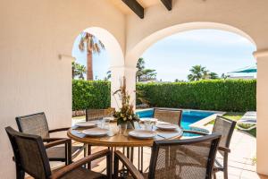 a patio with a table and chairs and a pool at Villas Begonias in Cala'n Bosch