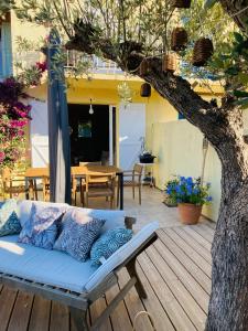 a couch sitting on a deck under a tree at MAZET RÉNOVE Golfe de st TROPEZ in Cogolin