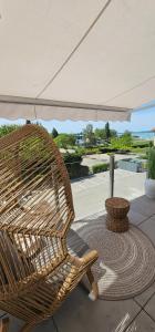 a wicker chair sitting under an umbrella on a patio at Infinity Apartman Lellemarine in Balatonlelle