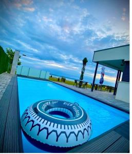 a swimming pool with a large tire on the deck at Infinity Apartman Lellemarine in Balatonlelle