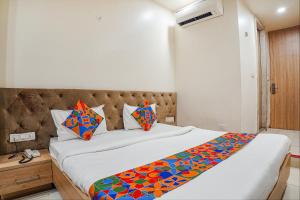 a bedroom with a large bed with colorful pillows at FabHotel Prime OM Palace in Bhopal