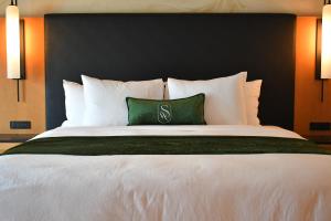a large white bed with a green pillow on it at The Swiftwater in Swiftwater