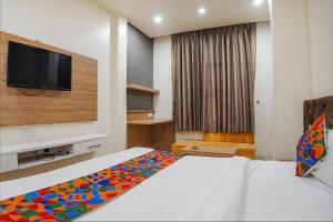 a hotel room with a bed and a flat screen tv at FabHotel Prime OM Palace in Bhopal