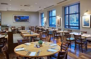 a restaurant with wooden tables and chairs and windows at DoubleTree by Hilton Swindon Hotel in Swindon