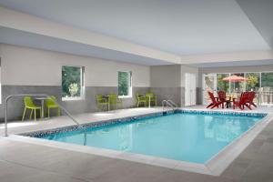 una piscina in una camera d'albergo con sedie e tavoli di Home2 Suites By Hilton Poughkeepsie a Poughkeepsie