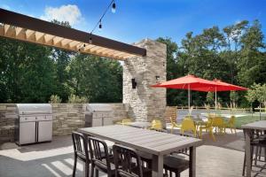 un patio con tavoli, sedie e ombrellone rosso di Home2 Suites By Hilton Poughkeepsie a Poughkeepsie
