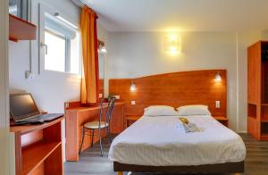 a bedroom with a bed and a desk with a laptop at Brit Hotel Reims La Pompelle in Reims +66 photos
