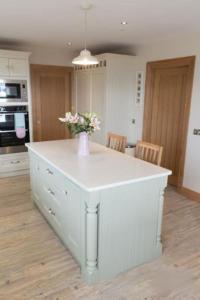 a kitchen with a white island with a vase of flowers at Sioscadh na Mara in Spiddal +19 photos