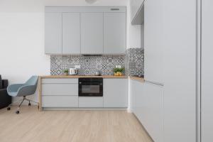a kitchen with white cabinets and a table and a chair at Metro Targówek One Bedroom Apartment for 4 with Furnished Balcony by Noclegi Renters in Warsaw +12 photos