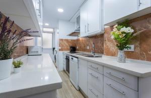 a kitchen with white cabinets and flowers in a vase at Plaza Caballo 3 Dormitorios Vistas in Jerez de la Frontera