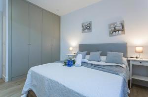 a white bedroom with a large bed with blue pillows at Plaza Caballo 3 Dormitorios Vistas in Jerez de la Frontera
