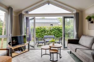 a living room with a couch and a tv at Modern chalet op de Veluwe in Epe