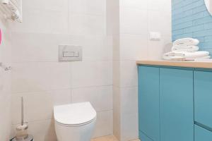 a white bathroom with a toilet and a sink at VacationClub - Moon Residence Apartament 14 in Ustronie Morskie
