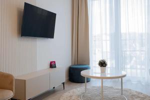 a living room with a table and a tv on a wall at VacationClub - Moon Residence Apartament 14 in Ustronie Morskie +4 photos