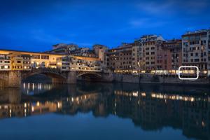 uma ponte sobre um rio numa cidade à noite em UNYCA - River View Suite em Florença