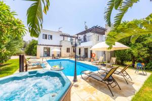 an outdoor swimming pool with a hot tub in front of a house at Villa Ay Kyriaki in Prodhromi