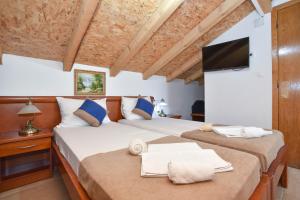 a bedroom with two beds and a tv on a wall at Villa Pedja Zec Exclusive 3+ in Budva
