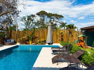 a pool with chairs and an umbrella next to a fence at Pousada Tribo Do Sol in Ubatuba