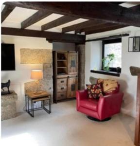 Beautiful Character Cottage - with Hot Tub في بودمين: غرفة معيشة مع كرسي احمر وطاولة