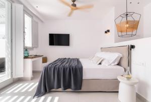 a white bedroom with a bed and a flat screen tv at Quartano Suites by Heliessa, Adults Only in Naousa