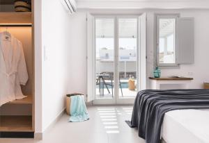 a white bedroom with a bed and a balcony at Quartano Suites by Heliessa, Adults Only in Naousa
